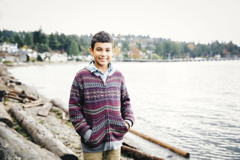 Mixed race boy walking on logs at lake