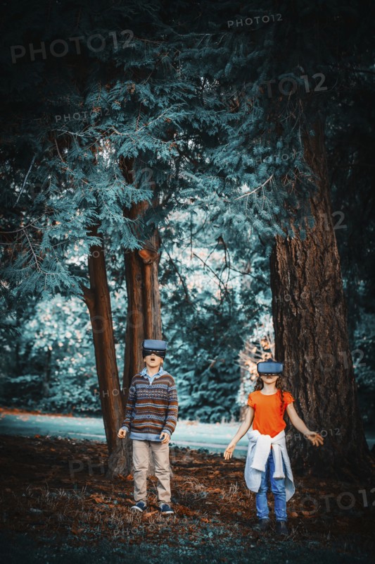 Mixed race children using virtual reality goggles outdoors
