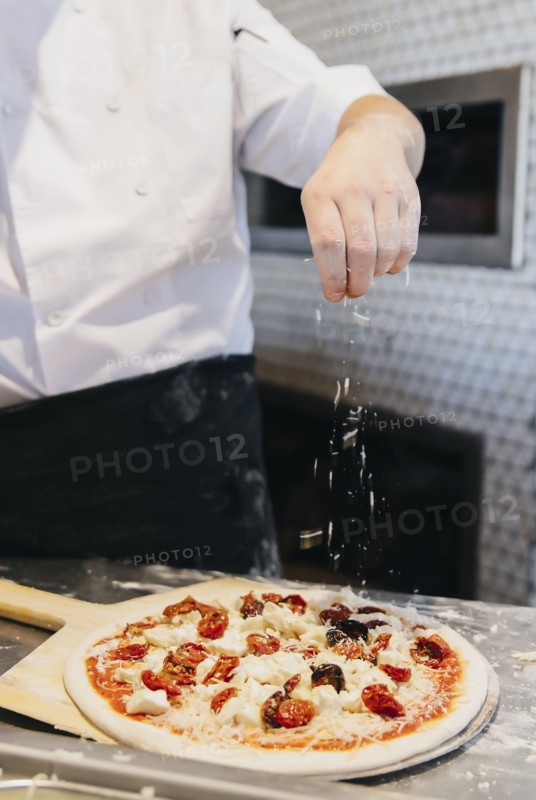 Chef making pizza in restaurant in kitchen