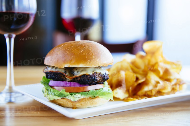Plate of cheeseburger and chips with wine