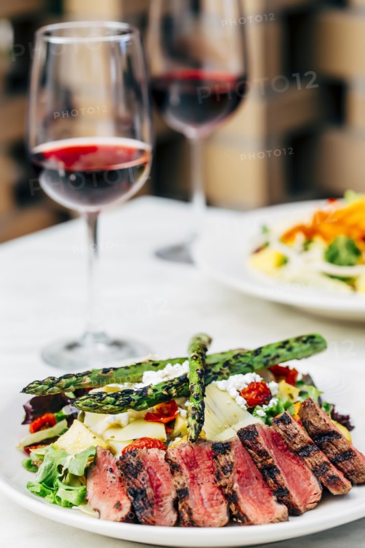 Plate of grilled meat and asparagus salad with wine