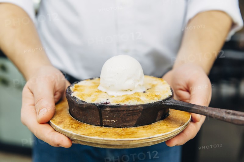 Caucasian waiter holding skillet dessert