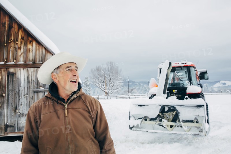 Caucasian farmer and tractor in snowy field