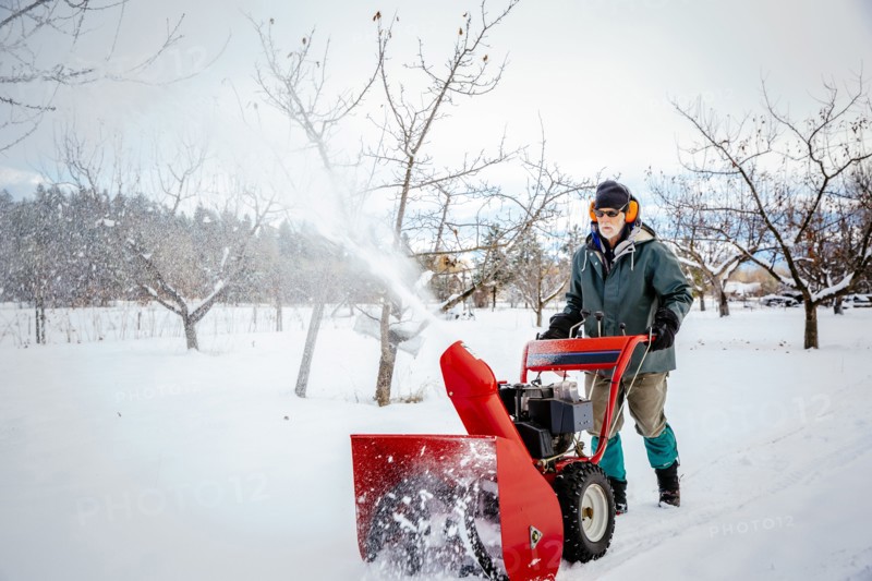 Caucasian man using snow blower in snowy field