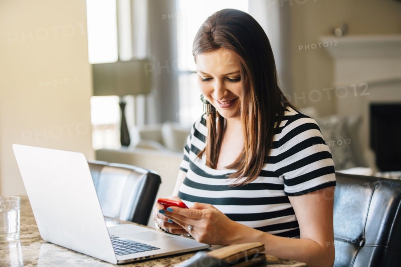 Hispanic woman using laptop and cell phone