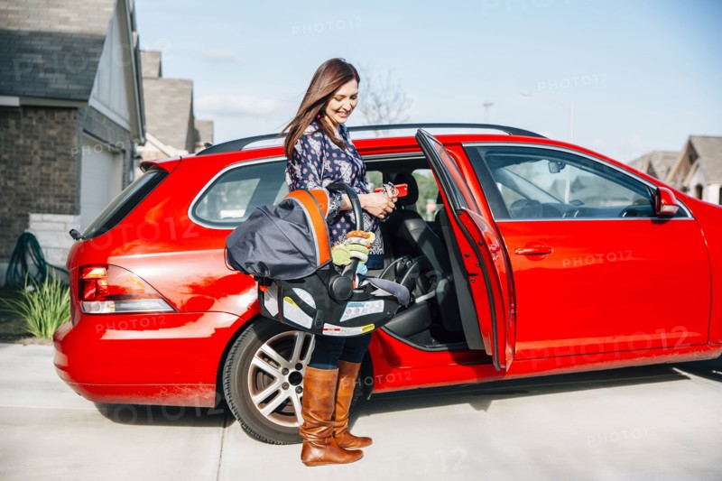 Hispanic woman carrying baby in car seat
