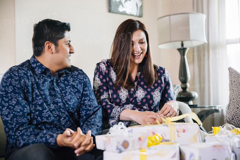 Hispanic couple opening gifts at baby shower