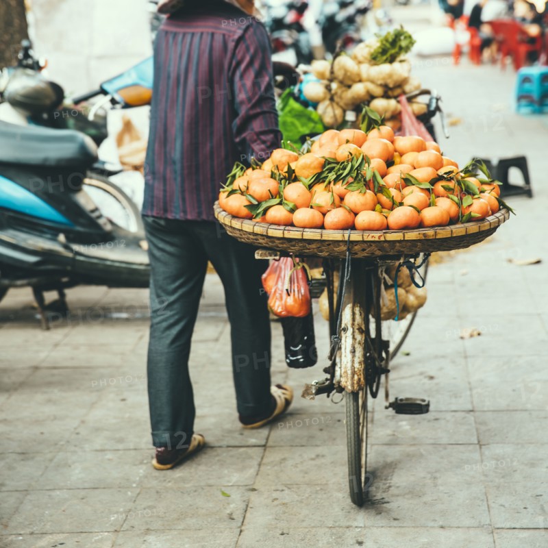 Vendor pushing bicycle with fruit for sale