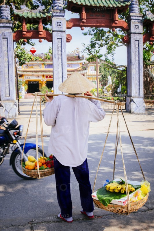 Vendor carrying fruit baskets on city sidewalk