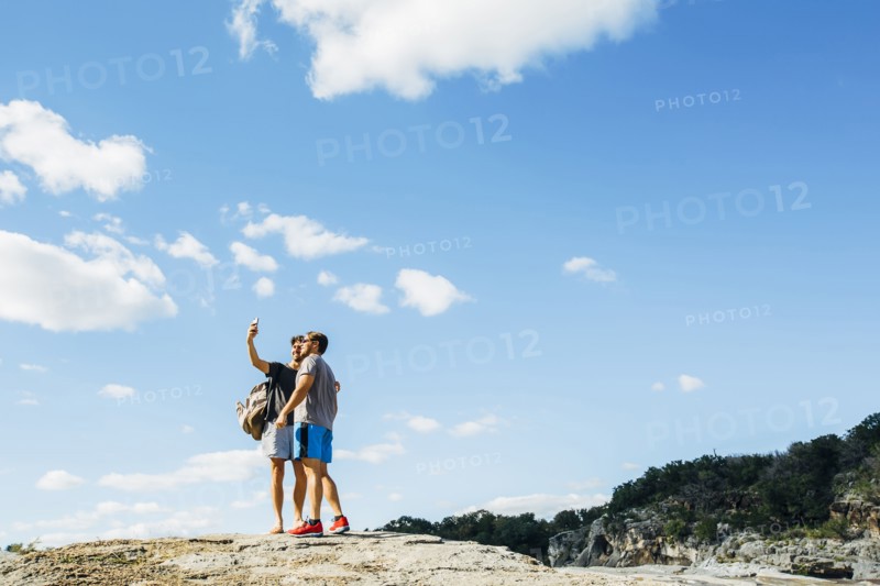Caucasian friends taking selfie on hilltop
