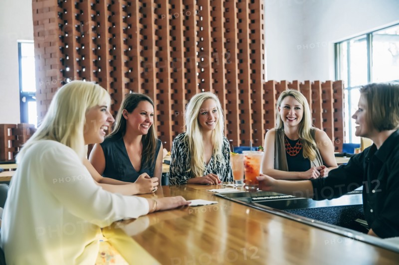 Caucasian bartender serving cocktail to women