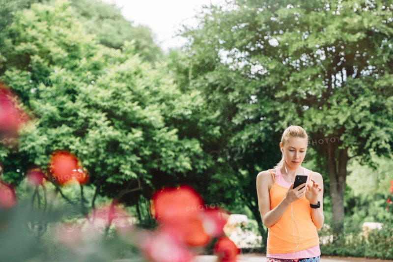 Caucasian woman using cell phone and earbuds outdoors