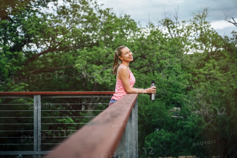 Caucasian woman leaning on banister holding water bottle