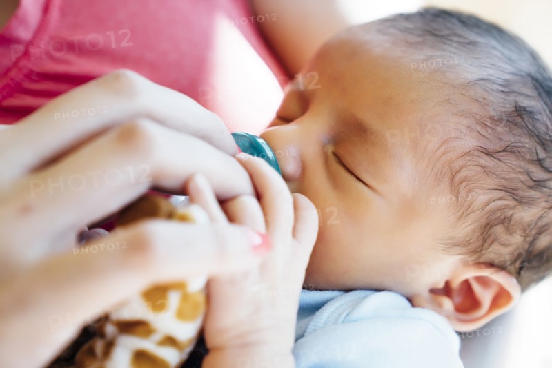 Hispanic woman holding baby boy with pacifier
