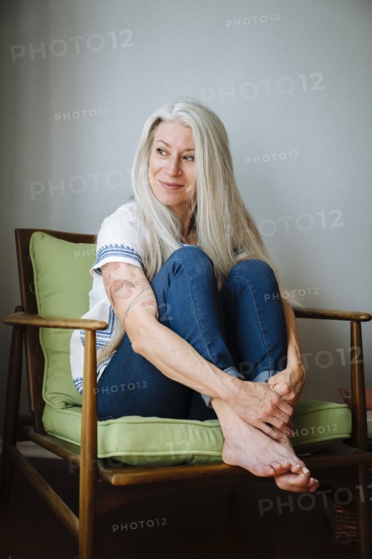Caucasian woman sitting in armchair looking away