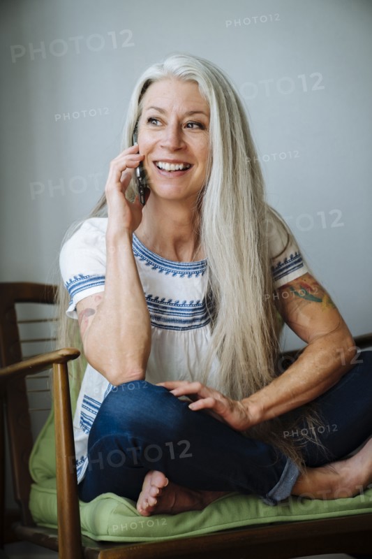Caucasian woman sitting in armchair talking on cell phone