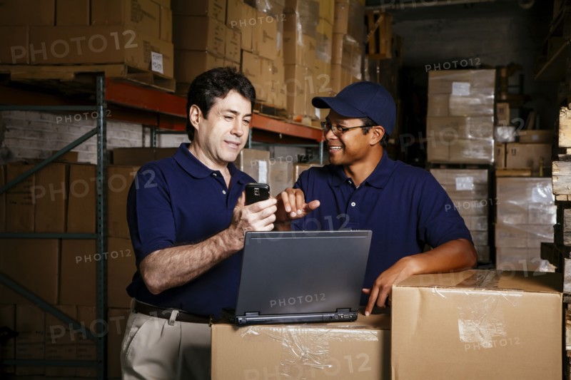 Warehouse workers using laptop and cell phone
