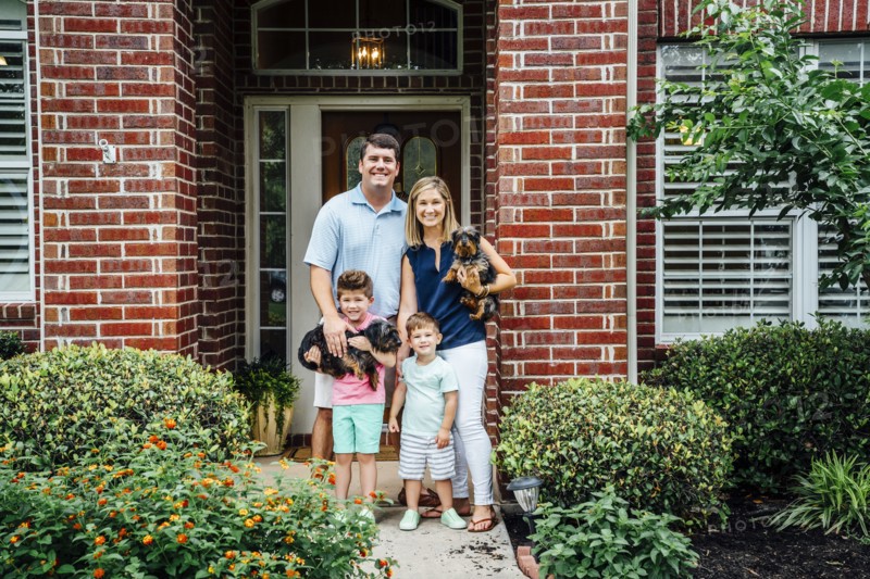 Proud Caucasian family posing at front stoop of house with dogs