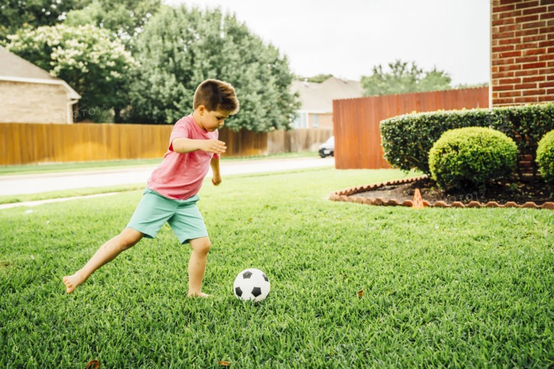 Caucasian boy kicking soccer ball on lawn