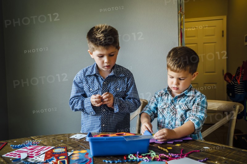 Caucasian boys making masks at table