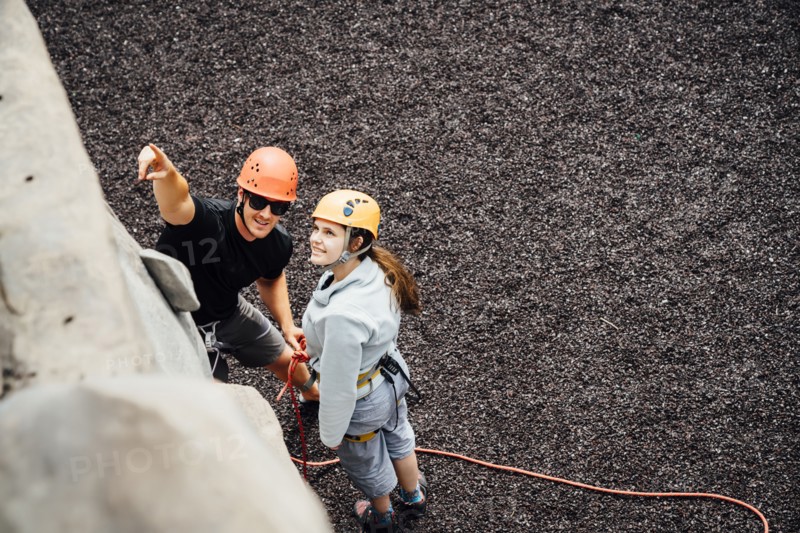 Caucasian man and woman pointing at rock climbing wall