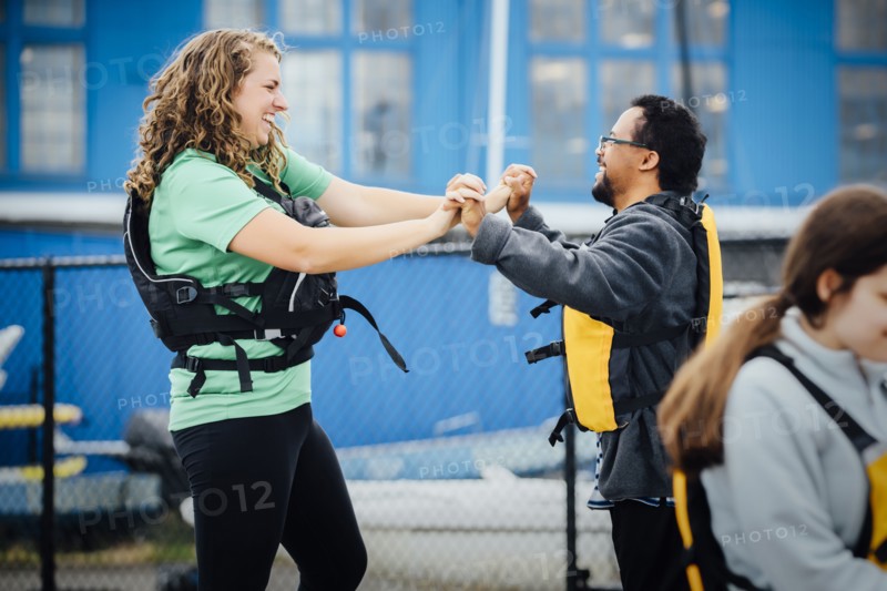 Man and woman wearing life-jackets holding hands