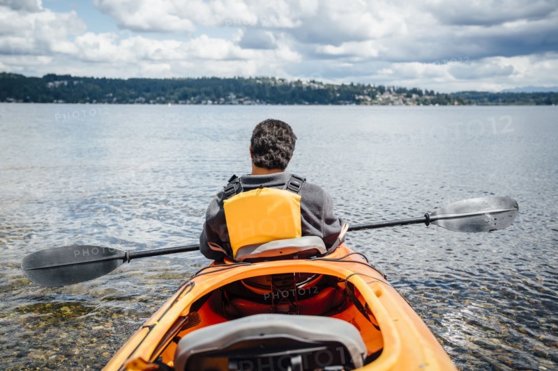 Mixed Rave man sitting in kayak holding paddle