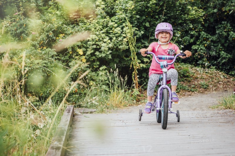 Mixed Race girl riding bicycle with training wheels