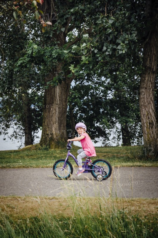 Mixed Race girl riding bicycle with training wheels