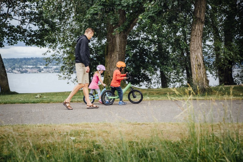 Father watching daughter and son riding bicycles