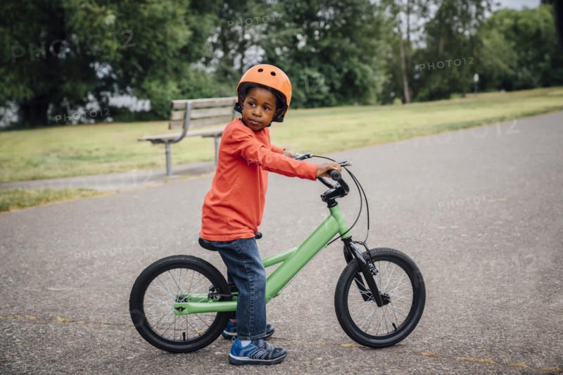 Black boy wearing helmet sitting on bicycle