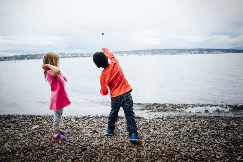 Boy and girl throwing rocks into river