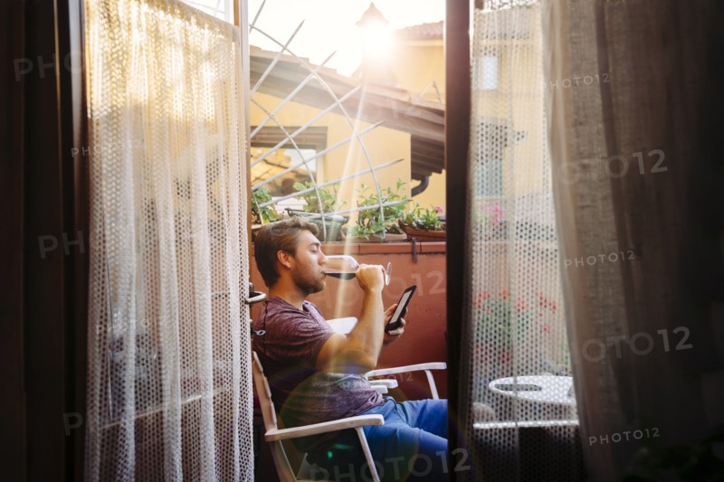 Caucasian man reading digital tablet drinking red wine