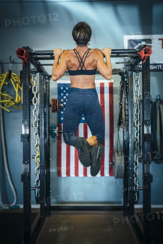 Caucasian woman doing chin-up in gymnasium