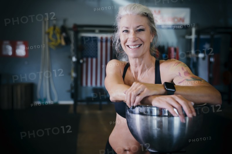 Smiling Caucasian woman leaning on bowl in gymnasium