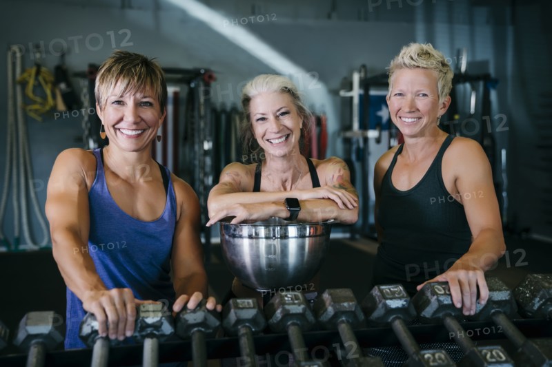 Smiling Caucasian women leaning on rack in gymnasium
