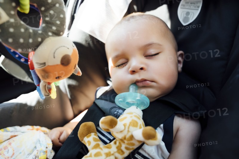 Mixed Race baby boy with pacifier sleeping in car seat