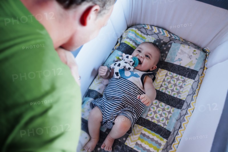 Father watching baby son in crib