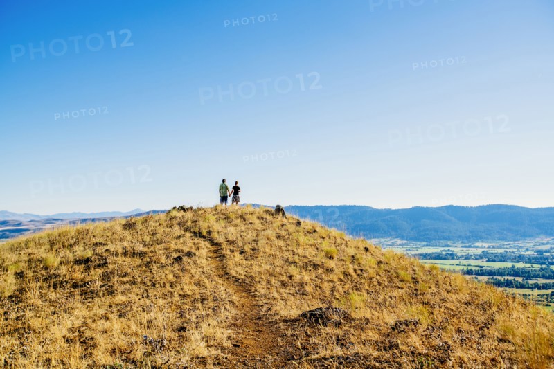 Distant Caucasian couple standing on hill holding hands