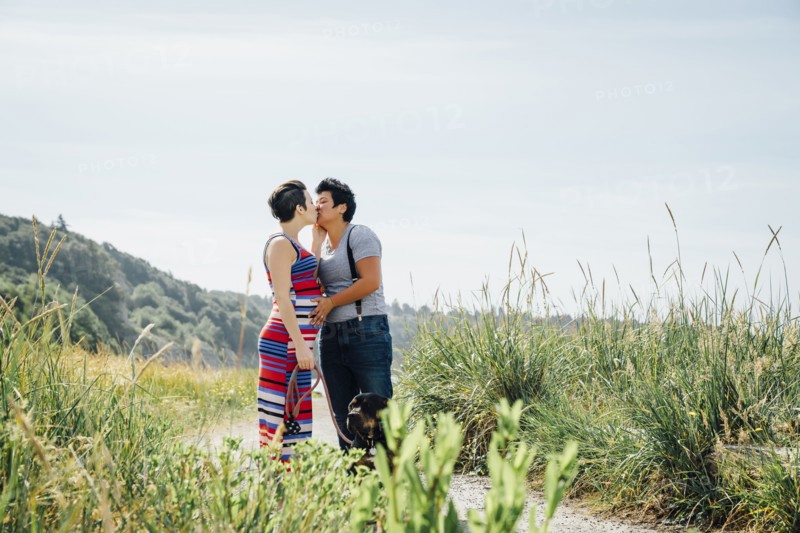 Pregnant lesbian couple kissing on path