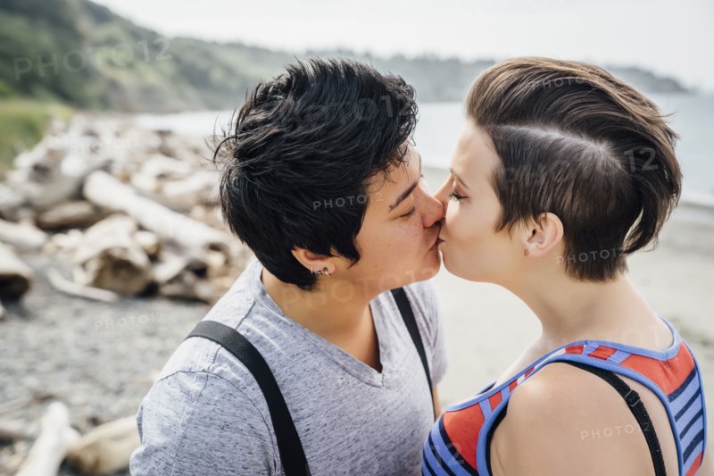 Pregnant lesbian couple kissing on beach
