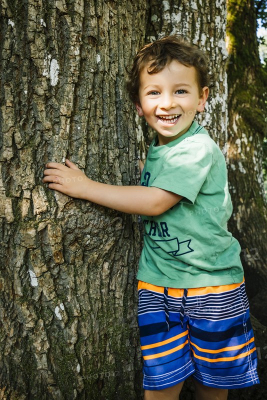 Portrait of smiling Caucasian boy hugging tree