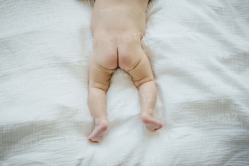 Naked buttocks of Mixed Race baby girl laying on blanket