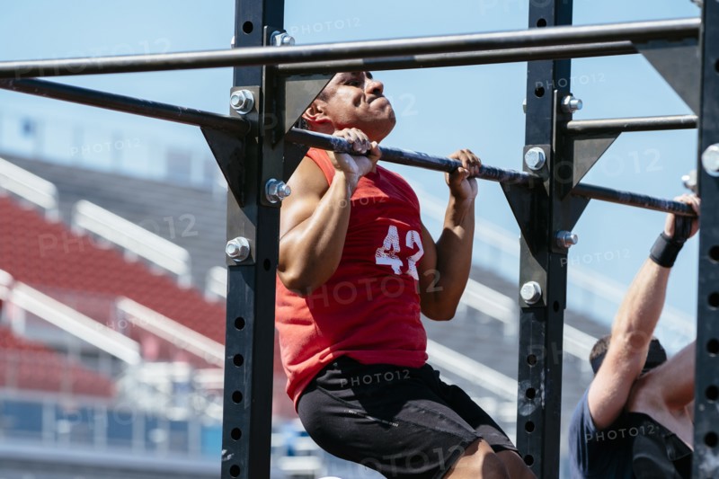 Hispanic man doing chin-ups outdoors