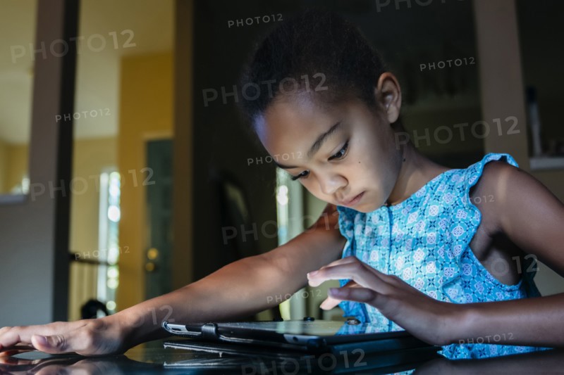 Mixed Race girl using digital tablet on table at night