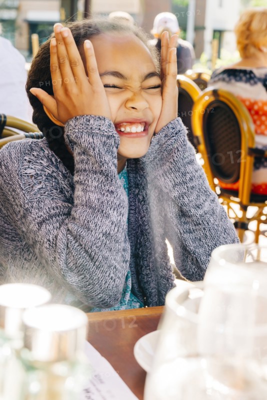 Smiling Mixed Race girl making a face at restaurant table