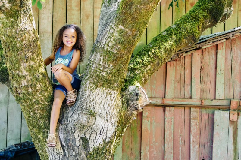 Mixed Race girl sitting in tree