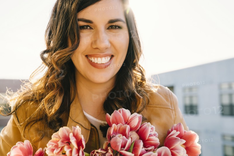 Portrait of smiling Mixed Race woman holding flowers