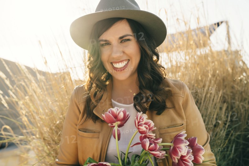 Portrait of smiling Mixed Race woman wearing hat holding flowers