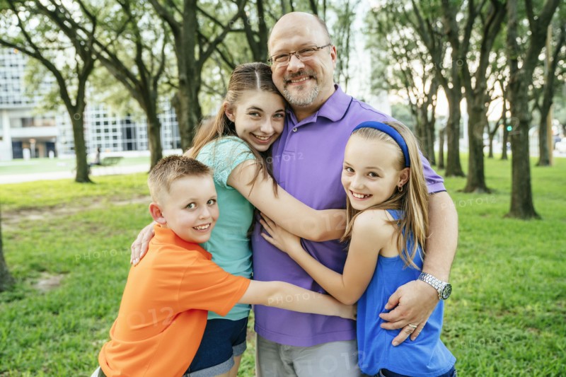 Portrait of Caucasian boy and girls hugging father in park